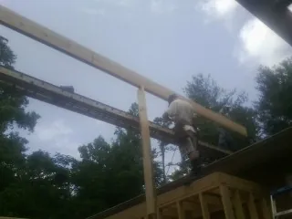 Carpenter setting a ridge beam over a new addition frame — Ice Dam Removal by Roofing Brothers in Mapleton