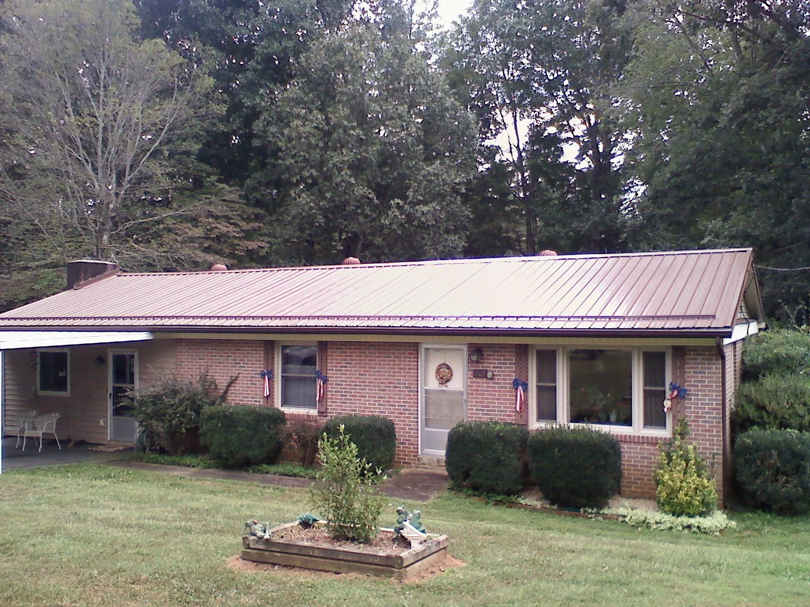 Bronze metal roof on a brick ranch home with a carport in Mapleton