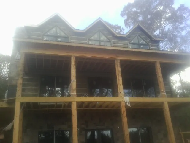 Dormers and porch framing on a large log home under construction — Roof Coating work by our crew in Mapleton